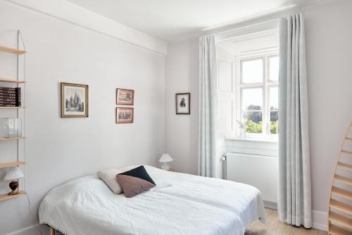 Habitación blanca con cama y ventana en Dallund Slot, en Søndersø