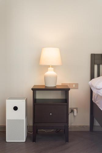 a lamp on a night stand next to a bed at The Lai Tiny House - Villa at Mae Kampong in Chiang Mai