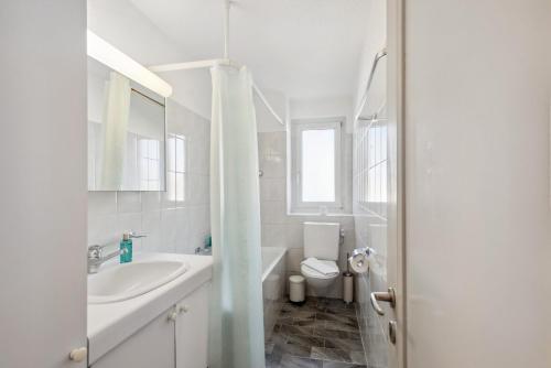 La salle de bains blanche est pourvue d'un lavabo et de toilettes. dans l'établissement Altwiesenstrasse 144, à Zurich