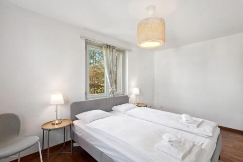 a white bedroom with a large bed and a window at Altwiesenstrasse 144 in Zürich