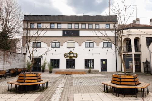 ein großes weißes Gebäude mit Bänken davor in der Unterkunft RIVA sleep & chill in Valjevo