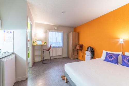 グッサンヴィルにあるMontempô apparthôtel CDG Goussainvilleのオレンジ色の壁のベッドルーム1室(ベッド1台付)