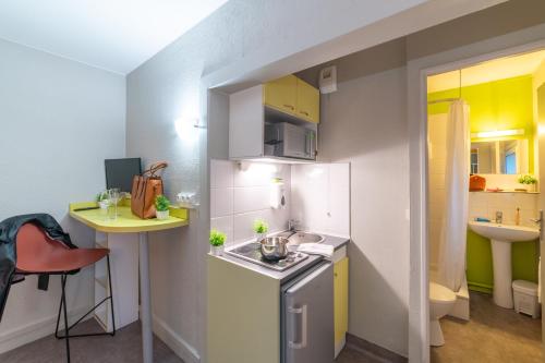 a small kitchen with a sink and a stove at Montempô apparthôtel CDG Goussainville in Goussainville