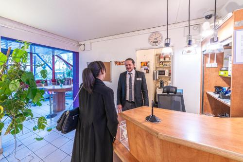 a man and a woman standing at a counter at Montempô apparthôtel CDG Goussainville in Goussainville