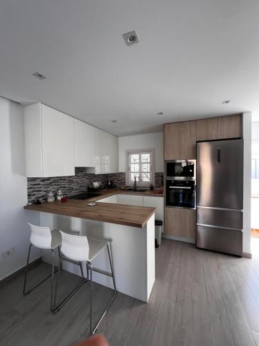 a kitchen with white cabinets and a stainless steel refrigerator at Residence Balcòn del Atlàntico Costa Adeje in Adeje