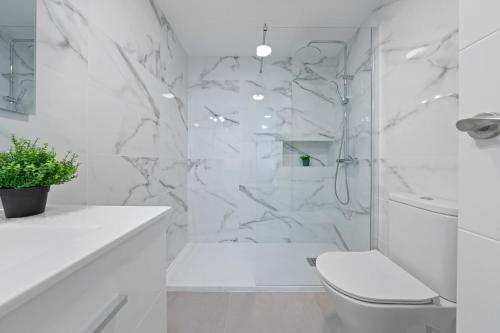 a white bathroom with a toilet and a shower at Alea Rentals - Acquamarina in La Pineda