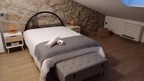 a bedroom with a bed and a stone wall at Casa da Póvoa in Seia