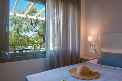 sypialnia z kapeluszem na łóżku z oknem w obiekcie Terra di Olive Thassos w mieście Potos