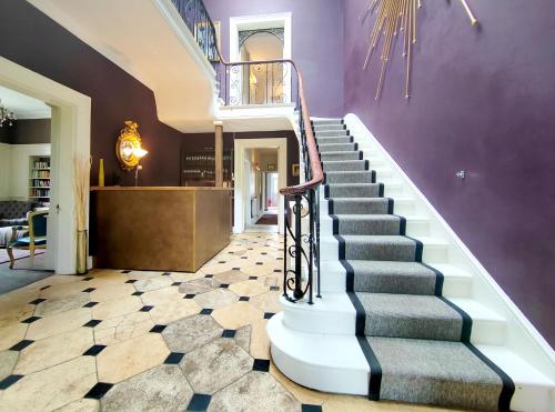 a staircase in a house with a purple wall at Sparkford Hall in Yeovil