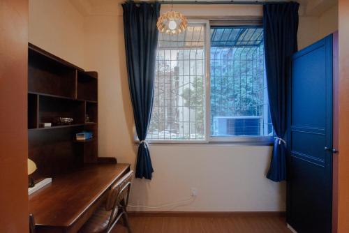 a room with a desk and a window with blue curtains at Arthur's Roof-Top in Chengdu