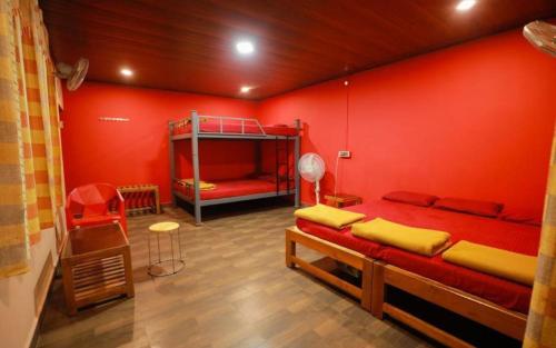 a room with two bunk beds and a red wall at Pepper Paradise by StayApart in Dandeli