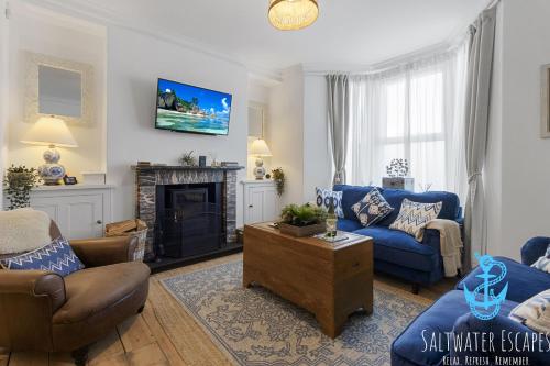 a living room with blue furniture and a fireplace at Little Fish in Brixham