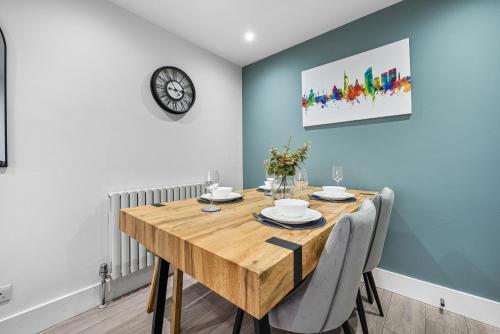 a dining room with a wooden table and a clock on the wall at 2 Bed Stunning Spacious Apt, Central Portsmouth, Parking - Sleeps 4 by Blue Puffin Stays in Portsmouth