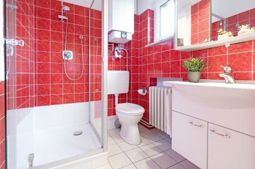 een rood betegelde badkamer met een toilet en een wastafel bij Haus Matthiesen in Malente