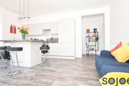 a living room with a blue couch and a kitchen at Stunning split level apartment with roof terrace in Lowestoft