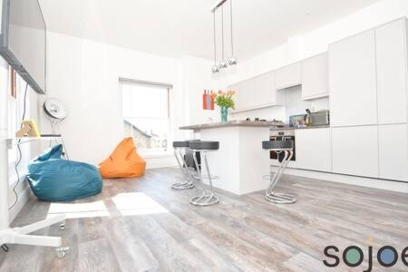 a large kitchen with white cabinets and an orange pillow at Stunning split level apartment with roof terrace in Lowestoft