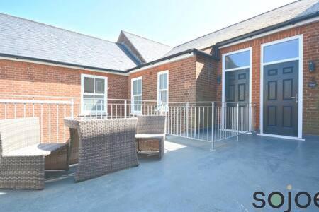 a patio with two chairs and a table and a building at Stunning split level apartment with roof terrace in Lowestoft