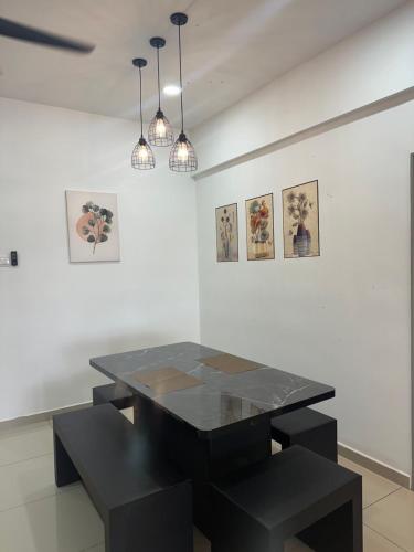 uma mesa preta e bancos numa sala com pinturas em Ulike~Homestay~C~3Room-The Venus em Sitiawan