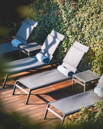three chairs sitting on a deck next to a hedge at Arborina Relais in La Morra