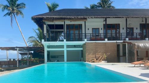 a house with a swimming pool in front of a building at Yapak Beach Villas in San Isidro
