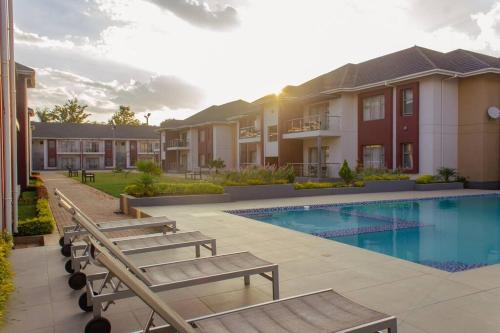 uma villa com uma piscina e dois bancos em Cherrywood Estate Apartment em Blantyre