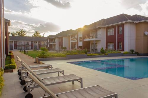 a villa with a swimming pool and two benches at Cherrywood Estate Apartment in Blantyre