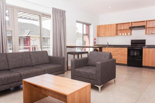 a living room with a couch and chairs and a kitchen at Cherrywood Estate Apartment in Blantyre