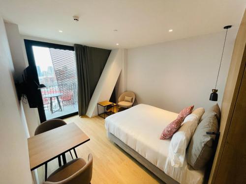 a bedroom with a bed and a table and a window at Tembo Barcelona in Barcelona