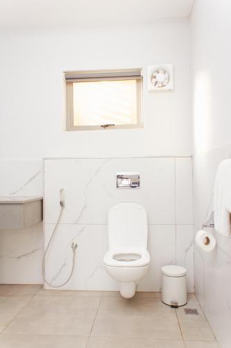a white bathroom with a toilet and a window at Cherrywood Estate Limited in Blantyre