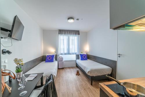 Cette petite chambre comprend un lit et une cuisine. dans l'établissement Montempô Apparthôtel Paris Noisy Le Sec, à Noisy-le-Sec