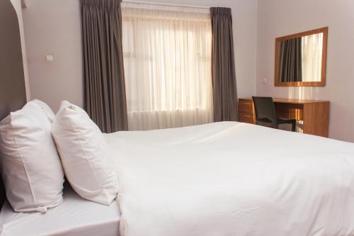 a bedroom with a white bed and a window at Cherrywood Estate Limited in Blantyre