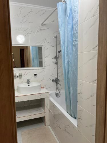 een witte badkamer met een wastafel en een douche bij 2 комнатная квартира in Taldykolʼ