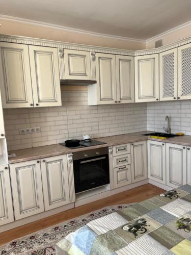 a kitchen with white cabinets and a black microwave at 2 комнатная квартира in Taldykolʼ