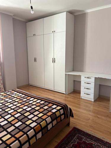 een slaapkamer met een bed, witte kasten en een bureau bij 2 комнатная квартира in Taldykolʼ