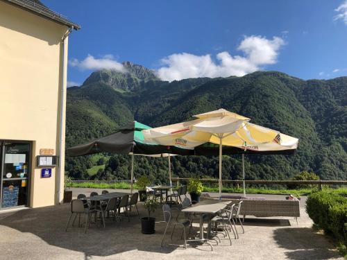 d'une terrasse avec des tables et des chaises et des montagnes en arrière-plan. dans l'établissement Auberge des isards, à Aydius