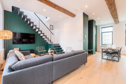 - un salon avec un canapé gris et un escalier dans l'établissement Spacious house 11 beds 8 bath 18 people - terrace., à Roubaix