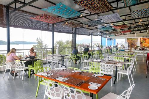 a restaurant with people sitting at tables and chairs at Langkapuri Resort Langkawi in Pantai Cenang