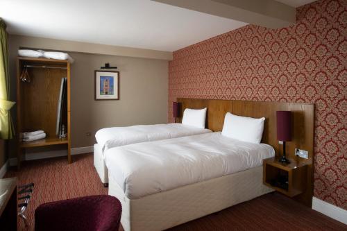 a hotel room with two beds and a red wall at The Romany Rye Wetherspoon in East Dereham