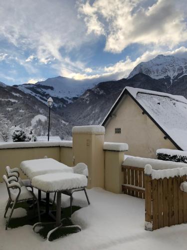 a balcony covered in snow with a table and chairs at Auberge des isards in Aydius