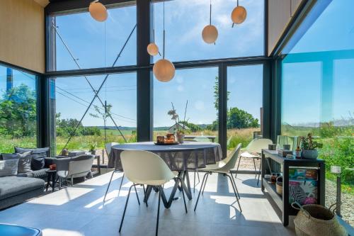 a dining room with a table and chairs and large windows at Arduenna Silva ecologic designer house in La-Roche-en-Ardenne