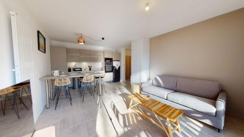 a living room and kitchen with a couch and a table at Haut Saint Georges - Un emplacement exceptionnel au centre-ville et au calme à quelques pas du lac marin in Soorts-Hossegor