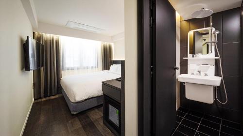 um quarto de hotel com uma cama e um lavatório em Moyen Hotel em Sokcho