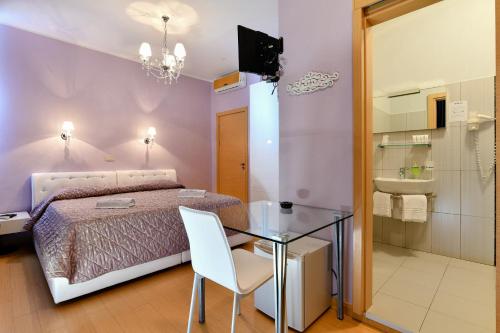 a bedroom with a bed and a glass table and a bathroom at HOTEL BLUMARIN in Lido di Jesolo