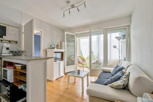 un salon avec un canapé et une cuisine dans l'établissement Appartement Abbra - Welkeys, à Cabourg