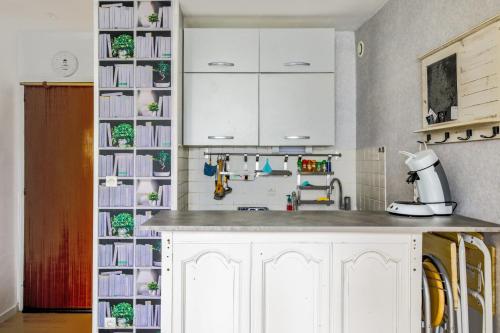 une cuisine avec des placards blancs et une étagère à livres dans l'établissement Appartement Abbra - Welkeys, à Cabourg