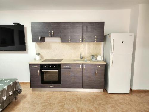een keuken met houten kasten en een witte koelkast bij Kati's Room in Eilat