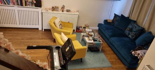 a living room with a blue couch and yellow chairs at Comfortable and Convenient in Hatfield