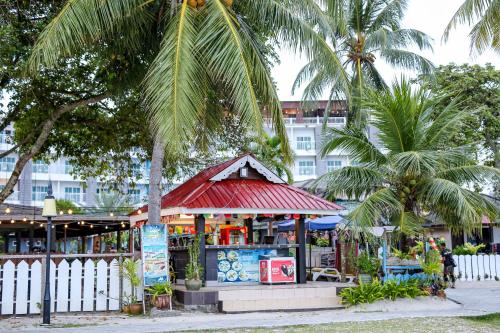 a gazebo with palm trees in front of a building at Langkapuri Resort Langkawi in Pantai Cenang