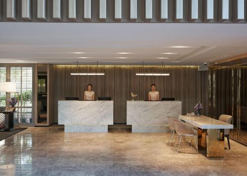 two people standing at a counter in a lobby at The Park Nine Hotel Suvarnabhumi - Free BKK Airport Shuttle in Lat Krabang