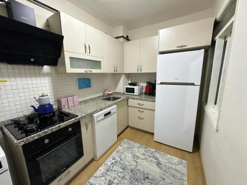 La cuisine est équipée de placards blancs et d'un réfrigérateur blanc. dans l'établissement APARTİST 2, à Istanbul